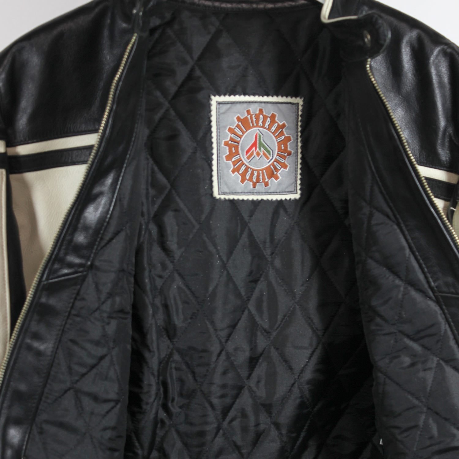 A used black and crème Tout Terrain Bad Boy women's leather jacket in a city style, size L. In good condition with minor signs of use and scratches, it has a stylish two-tone design and no built-in protectors.