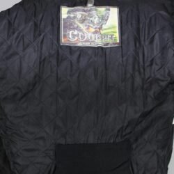 A used black Cockpit leather jacket in a vintage style, size 50/M. In fair condition, it has minor scratches and a characterful, naturally wrinkled appearance from use. It features a short connection zipper for pants and has no built-in protectors.
