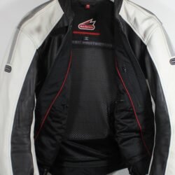 A used black and white Hein Gericke leather jacket in a women's Café-Racer style, size 44. In good condition with minor scratches, it features protection at the elbows, shoulders, and back, reflective elements, a full-length connection zipper, and a design intended to be waterproof.