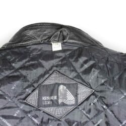 A used black Krawehl Leder vintage leather jacket in size 56. In good condition with minor scratches and a naturally wrinkled patina, it features reinforced leather panels on the elbows, shoulders, chest, and lower back, plus a short connection zipper for pants.