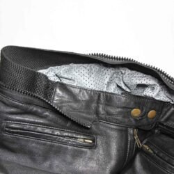 A pair of pre-owned black leather motorcycle trousers in a cafe-racer style, size 44. Condition is good with minor age-related wear including potential elastic weakening and light scratching on the reflective safety stripes. No protectors included