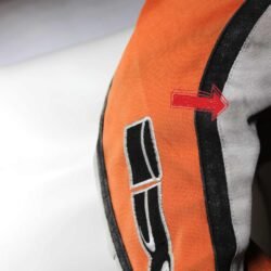 A used black, orange, and crème IXS 79 Racing Team textile jacket in size L. In fair condition with some wear, pulled threads, and potential fading, it features protection at the back, shoulders, and elbows, a removable thermal liner, and a full-length connection zipper.
