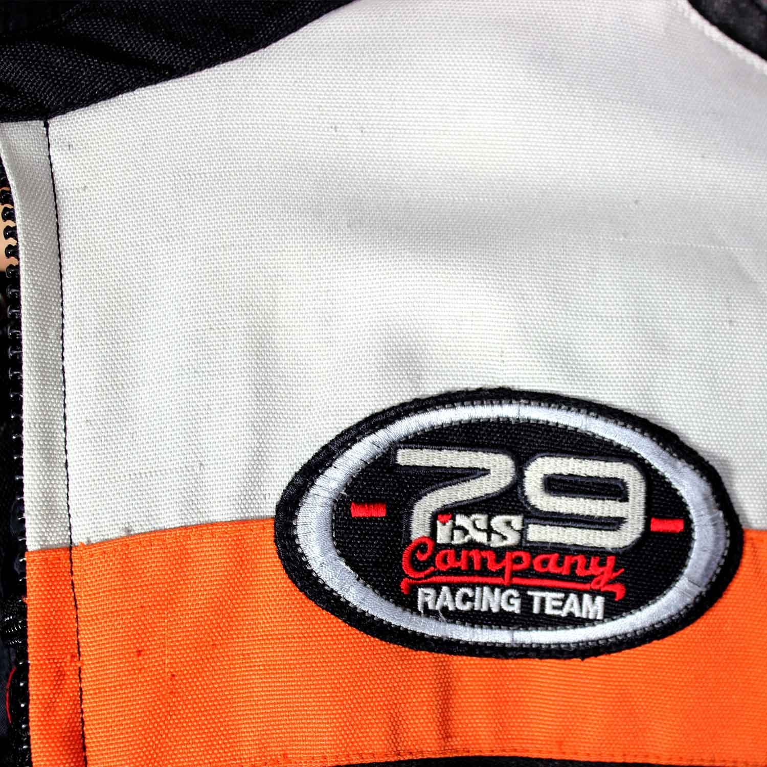 A used black, orange, and crème IXS 79 Racing Team textile jacket in size L. In fair condition with some wear, pulled threads, and potential fading, it features protection at the back, shoulders, and elbows, a removable thermal liner, and a full-length connection zipper.