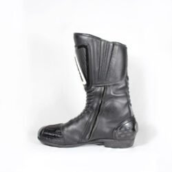 A pair of used black Gaerne G-RT racing motorcycle boots in size 43, made of leather. Features include heel, toe, gear lever, ankle, and shin protection, a non-slip oil-resistant sole, a wrap-around heel cup, and a double closure system with a zip and wide Velcro strap. Shows scratching on the plastic protectors.