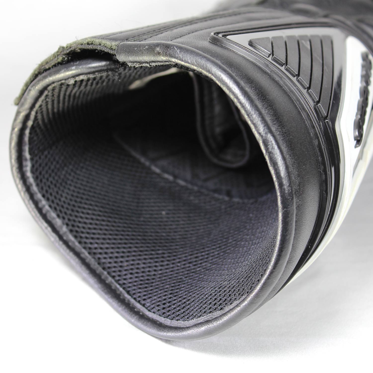 A pair of used black Gaerne G-RT racing motorcycle boots in size 43, made of leather. Features include heel, toe, gear lever, ankle, and shin protection, a non-slip oil-resistant sole, a wrap-around heel cup, and a double closure system with a zip and wide Velcro strap. Shows scratching on the plastic protectors.