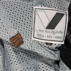 Used Vanucci black leather Café-Racer pants with hip and knee foam protection, featuring connection zippers and perforated ventilation. Shows minor wear and scratches.