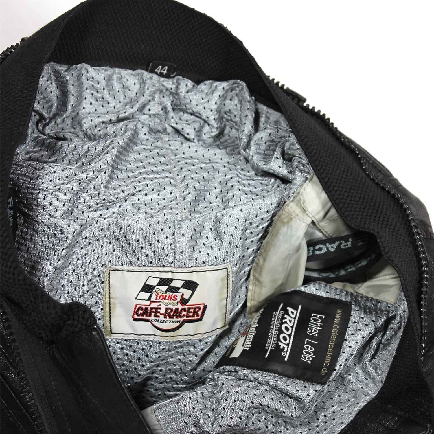 A pair of pre-owned black leather motorcycle trousers in a cafe-racer style, size 44. Condition is good with minor age-related wear including potential elastic weakening and light scratching on the reflective safety stripes. No protectors included