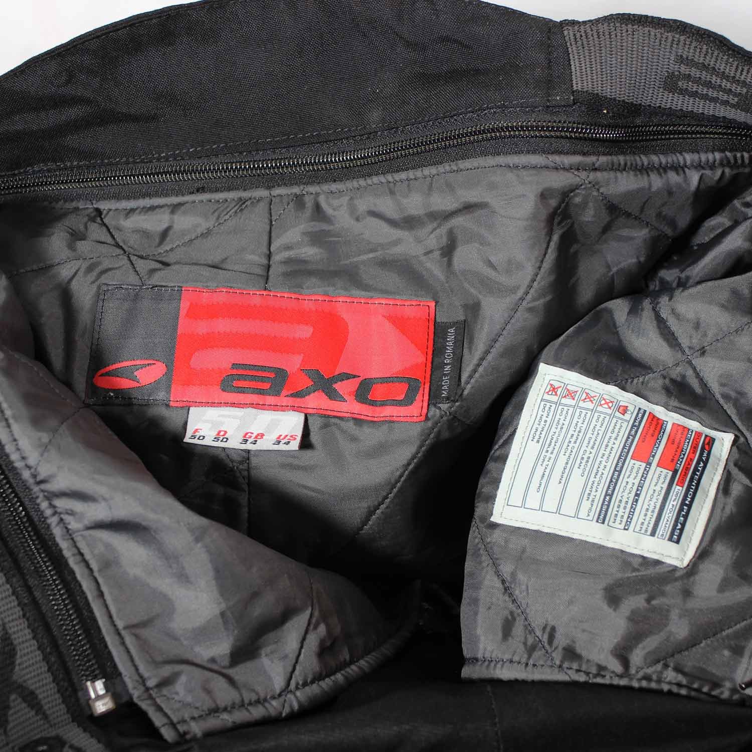 A pair of black AXO textile touring trousers in size 50. They feature a Miporex waterproof membrane and come with protectors for the knees and shins. The trousers are in fairly good condition with some wear marks and a slightly worn elastic waistband.