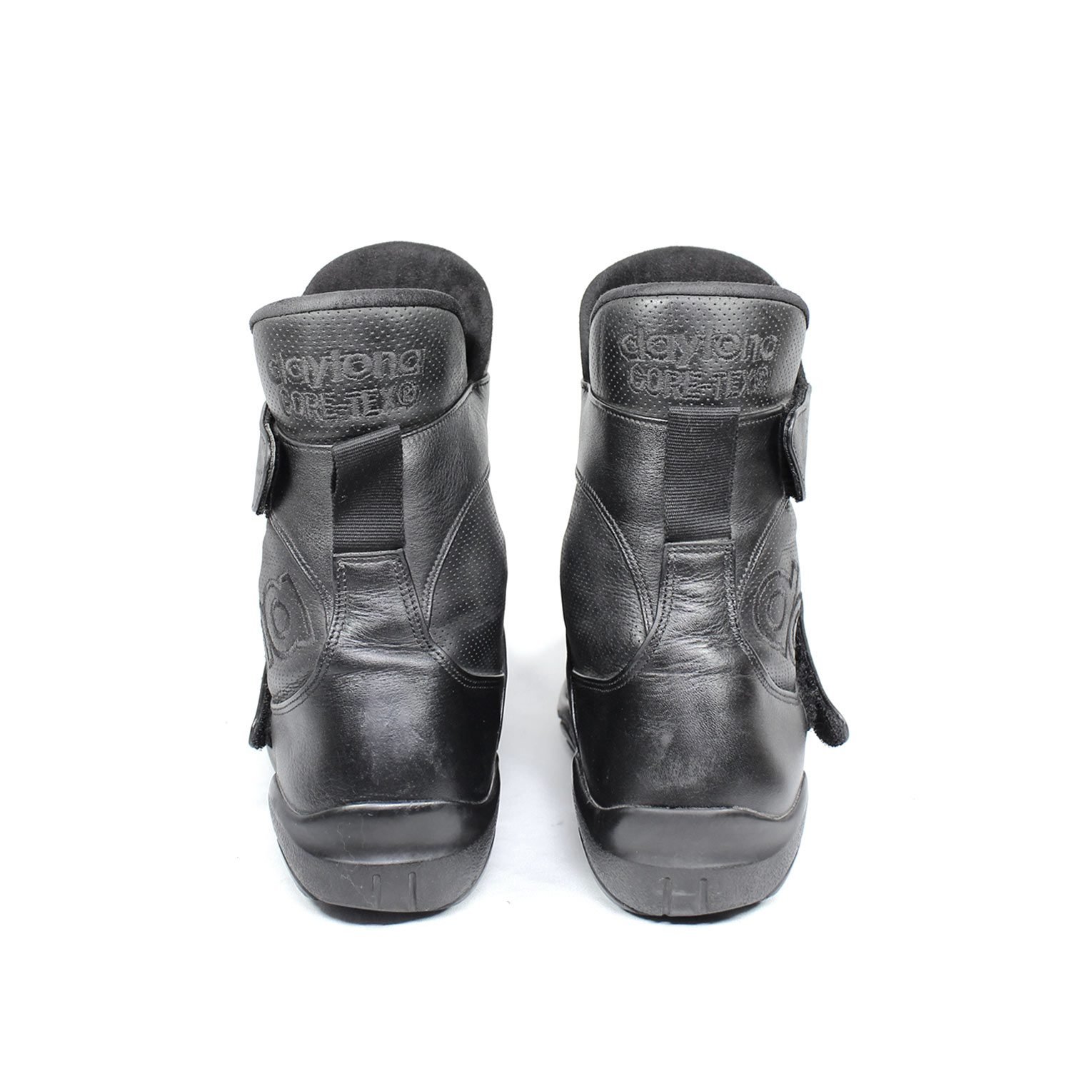 A pair of black leather touring boots, size 41, made in Germany. The boots feature a Gore-Tex membrane for waterproofing and have a high shaft. Key details include ankle protectors on both sides, a reinforced toe box, and a shin protector. The sole is a non-slip rubber with a tire tread pattern. The interior is padded with latex foam for comfort, and the insole is plastic-reinforced with a galvanized steel shank for torsion resistance. Minor wear is visible on the gear lever protection pad and the sole.