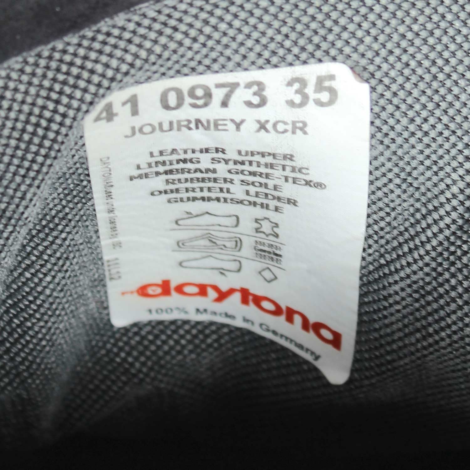 A pair of black leather touring boots, size 41, made in Germany. The boots feature a Gore-Tex membrane for waterproofing and have a high shaft. Key details include ankle protectors on both sides, a reinforced toe box, and a shin protector. The sole is a non-slip rubber with a tire tread pattern. The interior is padded with latex foam for comfort, and the insole is plastic-reinforced with a galvanized steel shank for torsion resistance. Minor wear is visible on the gear lever protection pad and the sole.