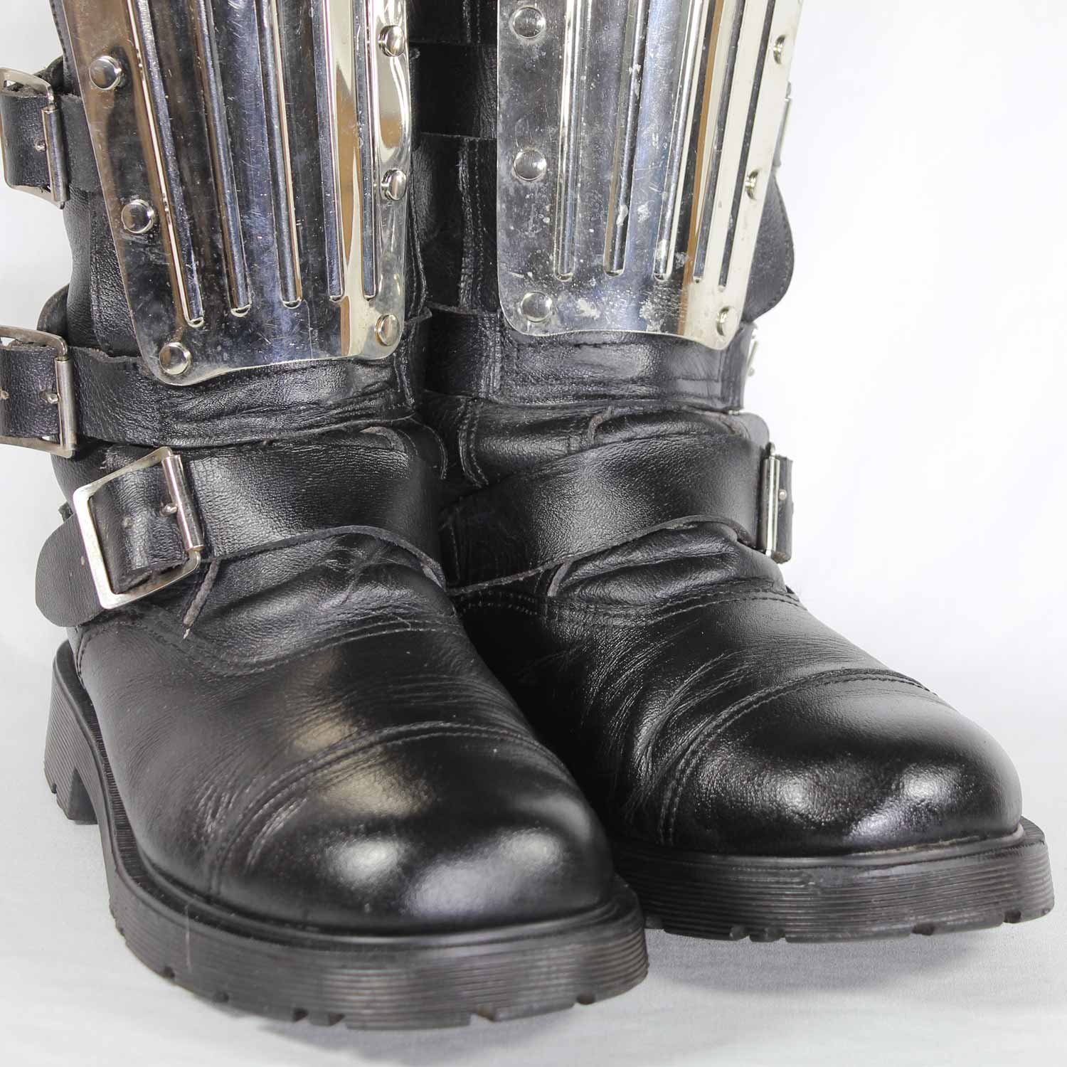 A pair of black leather Chopper-style cruiser boots by Underground Shoes in size 39. The boots feature a classic English design with metallic hardware accents and protective reinforcements on the toe, shin, and heel. They are in very good condition with minor wear marks.