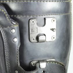 A pair of black ICON ONE THOUSAND 12" full-grain leather motorcycle boots, size 47, in good condition. Features ankle armor, reinforced shifter and shin protection, water-repellent leather, and a Goodyear welt construction. Shows typical wear, a missing screw on a back plaque, and a minor buckle flaw that does not hinder function.