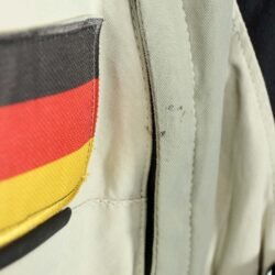 A black and beige Dainese D-Explorer adventure motorcycle jacket, size 58, in very good condition. Features an advanced modular flap system for ventilation, pockets for shoulder, elbow, and back protectors, and a removable rear exhaust vent. The jacket includes a replaceable country flag patch.