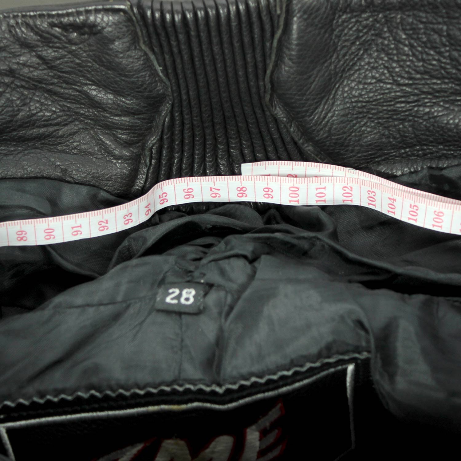 A pair of black ZME Racing leather motorcycle pants, size XXL/28 (91 cm waist), in very good condition. Features a racing and café-racer style with foam protectors at the knees and hips.